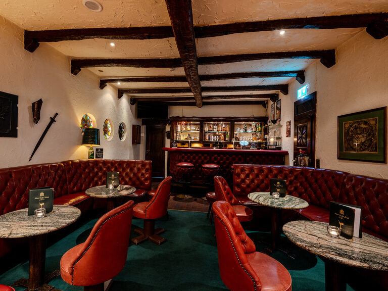 Rustikale Bar mit Sitzmöbeln aus rotem Leder im Hotel Seehof Berlin