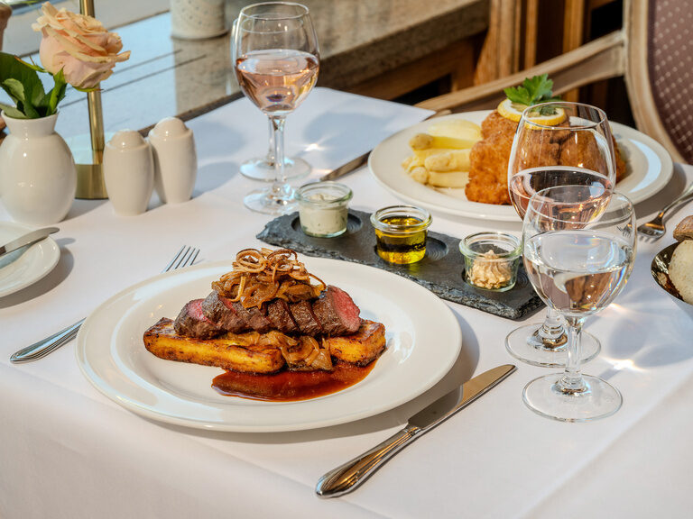 Elegant gedeckter Tisch mit schmackhafter Hauptspeise und Weingläsern im Ringhotel Seehof Berlin.
