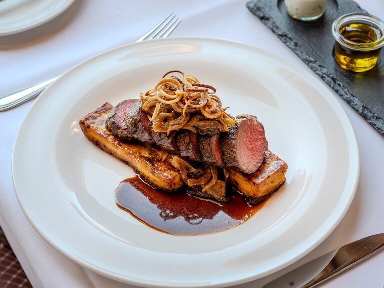 frische saisonale und regionale Küche - Teller mit Zwiebelrostbraten, Senfjus, Roastbeef, Zwiebeln und Kartoffelschnitte