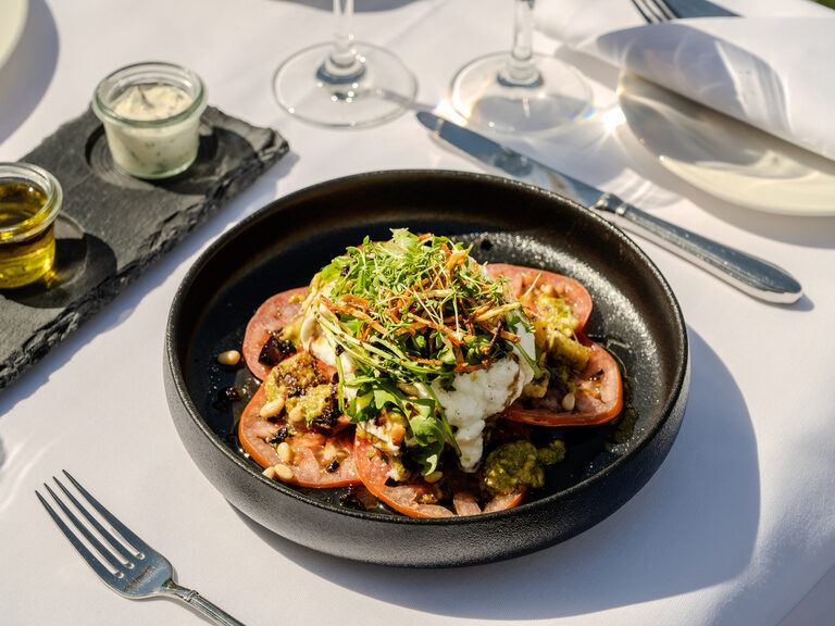 Ein eleganter Teller mit einem Tomanten-Mozarella Salat im Restaurant "AuLac" im Ringhotel Seehof Berlin